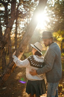 Güzel hipster çift birbirlerine bakıyor. Güzel şapkalar ve kazaklar giyen bir çift. Yaşam tarzı, parkta güneşli bir günde iki oyun mutlu çift. Gençlik, sevgi ve yaşam tarzı kavramı. Sonbaharda gün batımı 