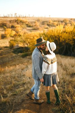 Güzel hipster çift birbirlerine bakıyor. Güzel şapkalar ve kazaklar giyen bir çift. Yaşam tarzı, parkta güneşli bir günde iki oyun mutlu çift. Gençlik, sevgi ve yaşam tarzı kavramı. Sonbaharda gün batımı 