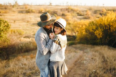 Güzel hipster çift birbirlerine bakıyor. Güzel şapkalar ve kazaklar giyen bir çift. Yaşam tarzı, parkta güneşli bir günde iki oyun mutlu çift. Gençlik, sevgi ve yaşam tarzı kavramı. Sonbaharda gün batımı 