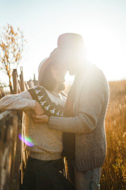 Güzel hipster çift birbirlerine bakıyor. Güzel şapkalar ve kazaklar giyen bir çift. Yaşam tarzı, parkta güneşli bir günde iki oyun mutlu çift. Gençlik, sevgi ve yaşam tarzı kavramı. Sonbaharda gün batımı 