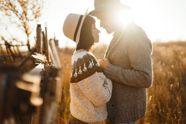 Güzel hipster çift birbirlerine bakıyor. Güzel şapkalar ve kazaklar giyen bir çift. Yaşam tarzı, parkta güneşli bir günde iki oyun mutlu çift. Gençlik, sevgi ve yaşam tarzı kavramı. Sonbaharda gün batımı 