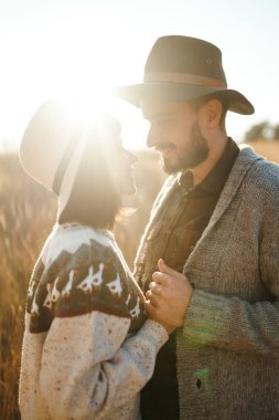Güzel hipster çift birbirlerine bakıyor. Güzel şapkalar ve kazaklar giyen bir çift. Yaşam tarzı, parkta güneşli bir günde iki oyun mutlu çift. Gençlik, sevgi ve yaşam tarzı kavramı. Sonbaharda gün batımı 