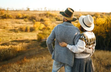 Güzel hipster çift birbirlerine bakıyor. Güzel şapkalar ve kazaklar giyen bir çift. Yaşam tarzı, parkta güneşli bir günde iki oyun mutlu çift. Gençlik, sevgi ve yaşam tarzı kavramı. Sonbaharda gün batımı 