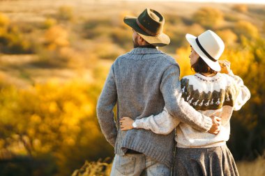 Güzel hipster çift birbirlerine bakıyor. Güzel şapkalar ve kazaklar giyen bir çift. Yaşam tarzı, parkta güneşli bir günde iki oyun mutlu çift. Gençlik, sevgi ve yaşam tarzı kavramı. Sonbaharda gün batımı 