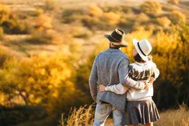 Güzel hipster çift birbirlerine bakıyor. Güzel şapkalar ve kazaklar giyen bir çift. Yaşam tarzı, parkta güneşli bir günde iki oyun mutlu çift. Gençlik, sevgi ve yaşam tarzı kavramı. Sonbaharda gün batımı 