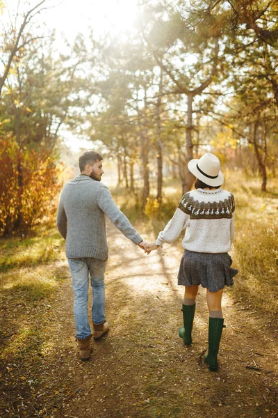 Lovely hipster couple looking at each other. Couple wearing beautiful hats and sweaters. Lifestyle, happy couple of two play on a sunny day in the park. The concept of youth, love and lifestyle. Sunset in autumn