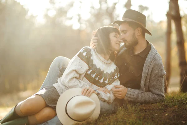 お互いを見て素敵なヒップスターカップル 美しい帽子とセーターを着たカップル ライフスタイル 公園で晴れた日に2つの遊びの幸せなカップル ライフスタイルの概念 秋の夕焼け — ストック写真