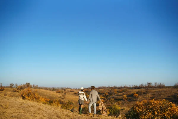 Lovely hipster couple looking at each other. Couple wearing beautiful hats and sweaters. Lifestyle, happy couple of two play on a sunny day in the park. The concept of youth, love and lifestyle. Sunset in autumn