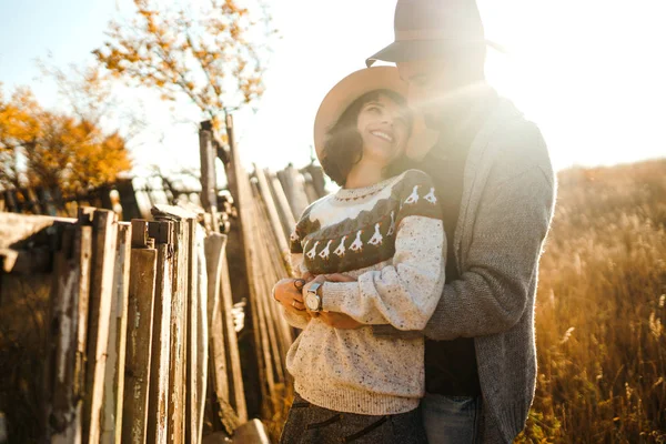 Lovely hipster couple looking at each other. Couple wearing beautiful hats and sweaters. Lifestyle, happy couple of two play on a sunny day in the park. The concept of youth, love and lifestyle. Sunset in autumn