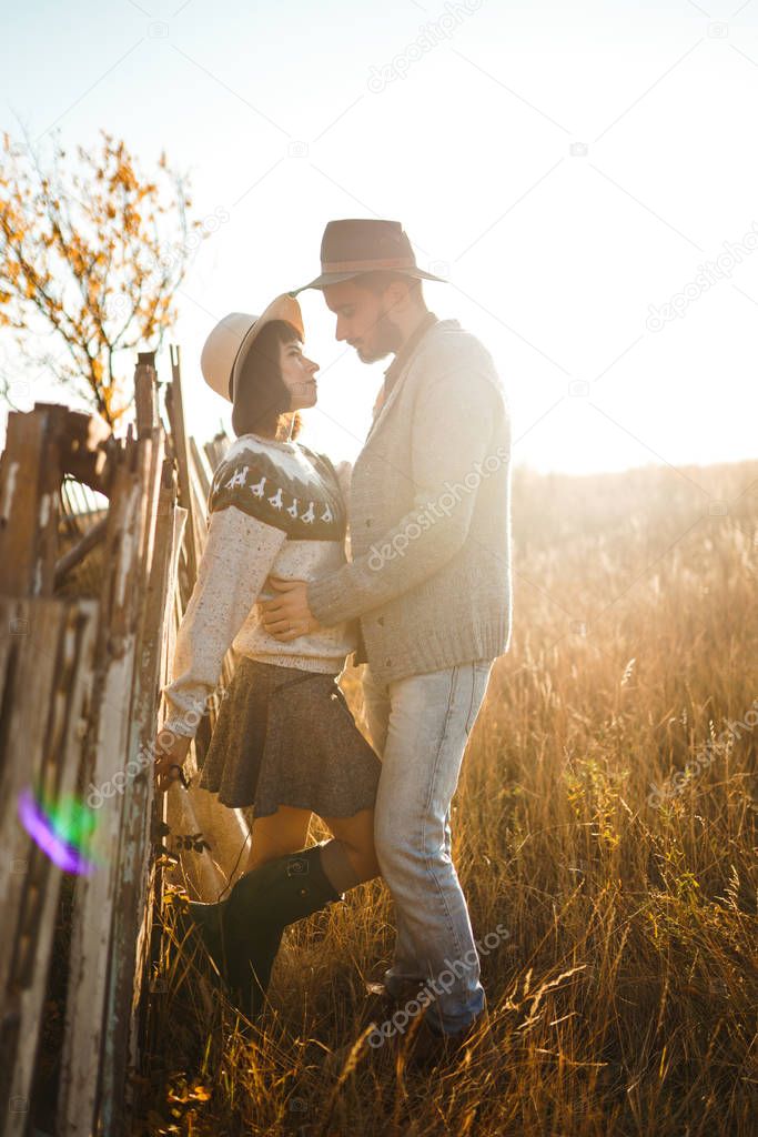Lovely hipster couple looking at each other. Couple wearing beautiful hats and sweaters. Lifestyle, happy couple of two play on a sunny day in the park. The concept of youth, love and lifestyle. Sunset in autumn 