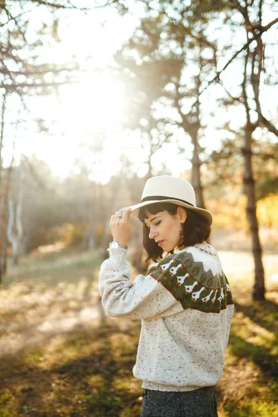 美丽的姑娘 日落时在森林里笑得很美 这个女孩穿着帽子 轻薄的毛衣和短裙 膝盖高的靴子 嬉皮士女孩的概念 生活方式 秋季风格 — 图库照片