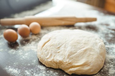 Hamur, merdane, yumurta ve un ahşap masada. Mutfak masasındaki malzemelerle birlikte çiğ pizza hamuru. Koyu arkaplan. 