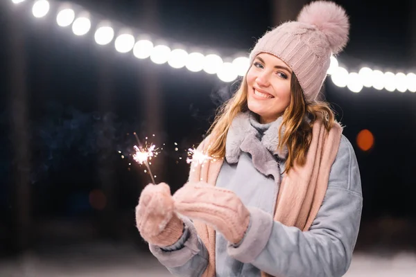 手に輝きを持つ美しい女の子 森の中で幸せな冬の時間 女の子は 薄手のニット帽 スカーフ ミトンで青いコートを着ています お祭りのガーランドライト クリスマス — ストック写真