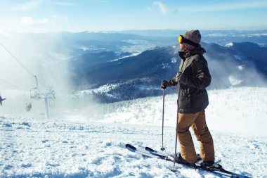 Dağlarda kayak yapan genç bir adam. Karlı dağlarda kayak yaparken, kış geliyor, kar yağıyor. Kışın aktif bir yaşam tarzı. Kayak merkezi sezonu açıldı. Kayak ekipmanları, patika. Olağanüstü kış sporları.