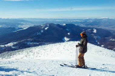 Dağlarda kayak yapan genç bir adam. Karlı dağlarda kayak yaparken, kış geliyor, kar yağıyor. Kışın aktif bir yaşam tarzı. Kayak merkezi sezonu açıldı. Kayak ekipmanları, patika. Olağanüstü kış sporları.