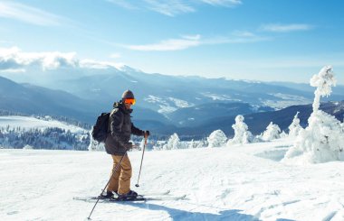 Dağlarda kayak yapan genç bir adam. Karlı dağlarda kayak yaparken, kış geliyor, kar yağıyor. Kışın aktif bir yaşam tarzı. Kayak merkezi sezonu açıldı. Kayak ekipmanları, patika. Olağanüstü kış sporları.