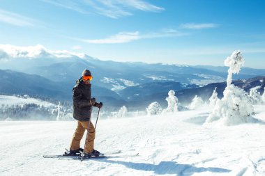 Dağlarda kayak yapan genç bir adam. Karlı dağlarda kayak yaparken, kış geliyor, kar yağıyor. Kışın aktif bir yaşam tarzı. Kayak merkezi sezonu açıldı. Kayak ekipmanları, patika. Olağanüstü kış sporları.
