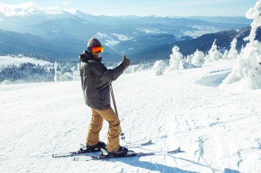 Dağlarda kayak yapan genç bir adam. Karlı dağlarda kayak yaparken, kış geliyor, kar yağıyor. Kışın aktif bir yaşam tarzı. Kayak merkezi sezonu açıldı. Kayak ekipmanları, patika. Olağanüstü kış sporları.