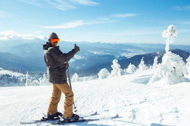 Dağlarda kayak yapan genç bir adam. Karlı dağlarda kayak yaparken, kış geliyor, kar yağıyor. Kışın aktif bir yaşam tarzı. Kayak merkezi sezonu açıldı. Kayak ekipmanları, patika. Olağanüstü kış sporları.