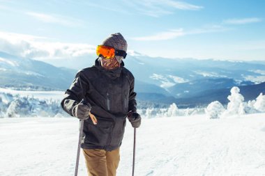 Dağlarda kayak yapan genç bir adam. Karlı dağlarda kayak yaparken, kış geliyor, kar yağıyor. Kışın aktif bir yaşam tarzı. Kayak merkezi sezonu açıldı. Kayak ekipmanları, patika. Olağanüstü kış sporları.