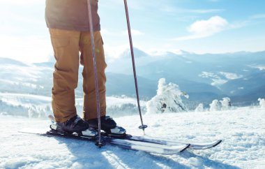 Dağlarda kayak yapan genç bir adam. Karlı dağlarda kayak yaparken, kış geliyor, kar yağıyor. Kışın aktif bir yaşam tarzı. Kayak merkezi sezonu açıldı. Kayak ekipmanları, patika. Olağanüstü kış sporları.