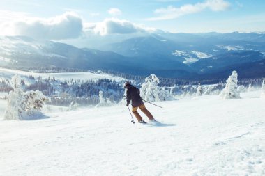 Dağlarda kayak yapan genç bir adam. Karlı dağlarda kayak yaparken, kış geliyor, kar yağıyor. Kışın aktif bir yaşam tarzı. Kayak merkezi sezonu açıldı. Kayak ekipmanları, patika. Olağanüstü kış sporları.