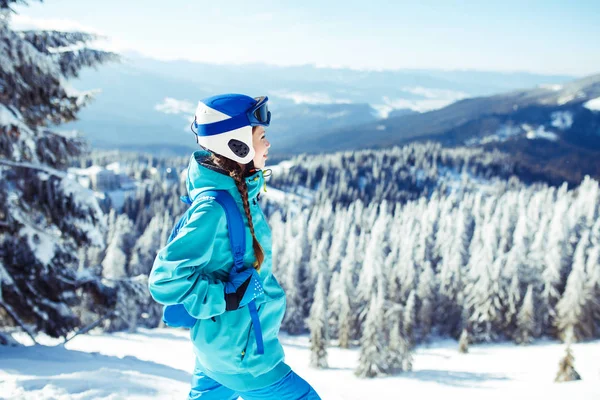 一个年轻的女孩喜欢冬季美景 一个穿着冬衣 头戴蓝色头盔 身穿夹克的漂亮姑娘在山里度过了一段美好的时光 自然的概念 — 图库照片