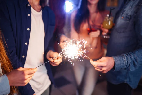 一群快乐的人在聚会上燃起火花 微笑着 年轻人在一起庆祝新年 朋友们点燃了火花 朋友们喜欢在晚上和火花在一起 模糊的背景 — 图库照片