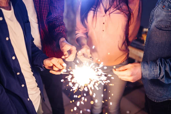 一群快乐的人在聚会上燃起火花 微笑着 年轻人在一起庆祝新年 朋友们点燃了火花 朋友们喜欢在晚上和火花在一起 模糊的背景 — 图库照片
