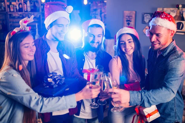 Friends celebrating new year\'s together. Portrait of Friends With Drinks Enjoying Cocktail Party. Young people laugh. Group of beautiful young people in Santa hats. Blur Background.