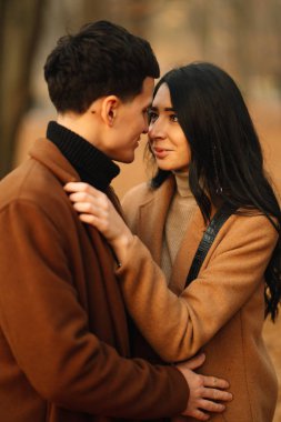 Ormanda güzel bir sonbahar gününde dışarıda şık genç bir çift. Birbirine aşık genç bir çift, bir sonbahar günü el ele tutuşup parkta yürüyorlar. Gençlik, aşk ve yaşam tarzı kavramı.