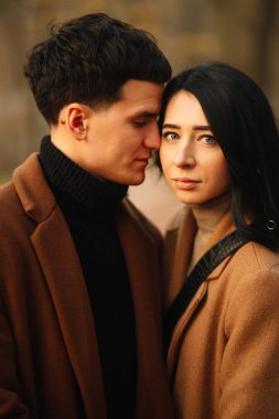 Ormanda güzel bir sonbahar gününde dışarıda şık genç bir çift. Birbirine aşık genç bir çift, bir sonbahar günü el ele tutuşup parkta yürüyorlar. Gençlik, aşk ve yaşam tarzı kavramı.