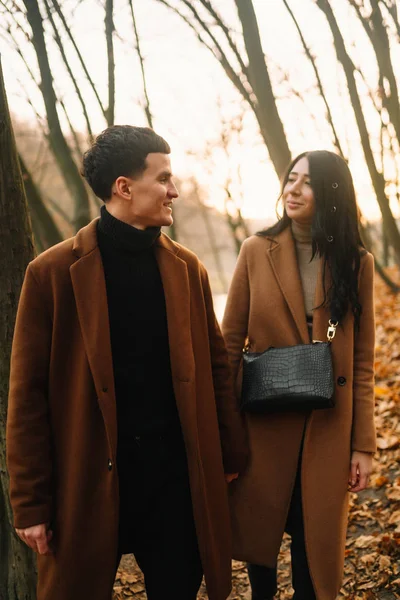 在一个美丽的秋天的森林里 一对时髦的年轻夫妇在户外 一对恋爱中的年轻夫妇在秋天的一天牵着手穿过一个公园 爱情和生活方式的概念 — 图库照片