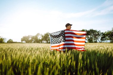 4 Temmuz 'da. Ulusal Amerikan bayrağı taşıyan vatansever bir adam. Genç adam gururla Amerikan bayrağı sallıyor. Bağımsızlık Günü. 