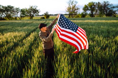 4 Temmuz 'da. Ulusal Amerikan bayrağı taşıyan vatansever bir adam. Genç adam gururla Amerikan bayrağı sallıyor. Bağımsızlık Günü. 