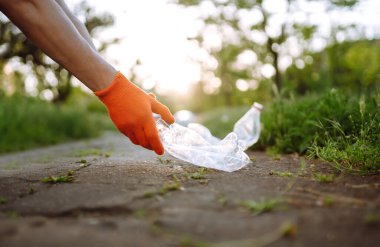 Erkekler parkta temizlik için plastik çöp toplar. Koruyucu eldiven giyen gönüllü şişe plastiği topluyor. Çevresel koruma, ekolojik kavram. Atık geri dönüşümü.