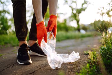 Erkekler parkta temizlik için plastik çöp toplar. Koruyucu eldiven giyen gönüllü şişe plastiği topluyor. Çevresel koruma, ekolojik kavram. Atık geri dönüşümü.