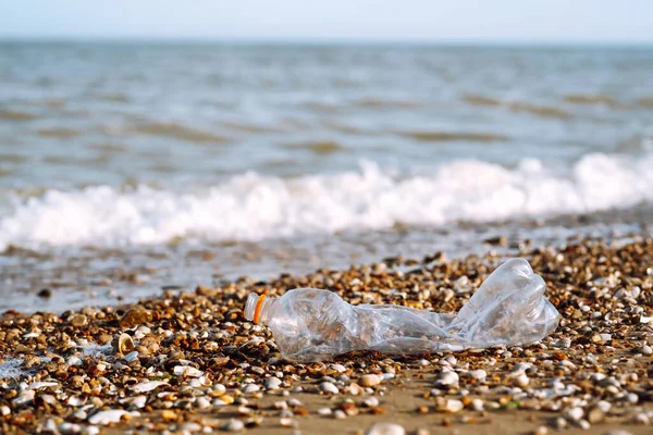 Empty plastic bottle on sea beach. Seashore and water pollution concept. Environmental protection, ecological concept. Waste recycling.