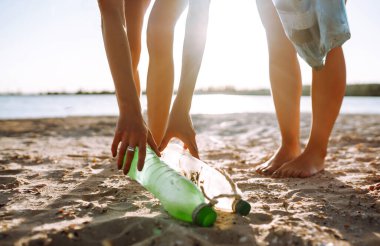 Kızlar sahilde çöp ve plastik şişe temizler. Ekoloji ve çevre koruma kavramı.