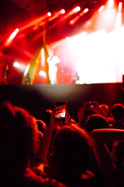 Hand with a smartphone records live music festival, Taking photo of concert stage. Youth, party, vacation concept.