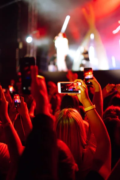 Hand with a smartphone records live music festival, Taking photo of concert stage. Youth, party, vacation concept.