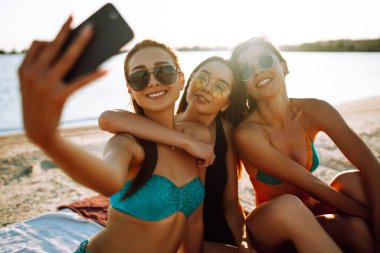 Genç kızlar sahilde selfie çeker. Plaj tatili ve yaz tatili konsepti.