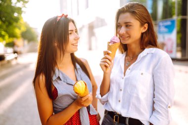 İki genç bayan arkadaş eğleniyor ve dondurma yiyor. Genç kadınlar yaz ve tatilin tadını çıkarıyor. 