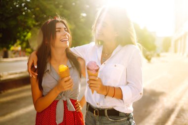 İki genç bayan arkadaş eğleniyor ve dondurma yiyor. Genç kadınlar yaz ve tatilin tadını çıkarıyor. 