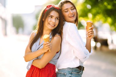 İki genç bayan arkadaş eğleniyor ve dondurma yiyor. Genç kadınlar yaz ve tatilin tadını çıkarıyor. 