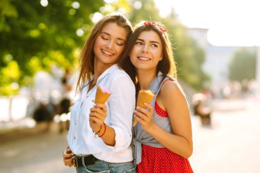 İki genç bayan arkadaş eğleniyor ve dondurma yiyor. Genç kadınlar yaz ve tatilin tadını çıkarıyor. 