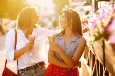 İki genç bayan arkadaş eğleniyor ve dondurma yiyor. Genç kadınlar yaz ve tatilin tadını çıkarıyor. 