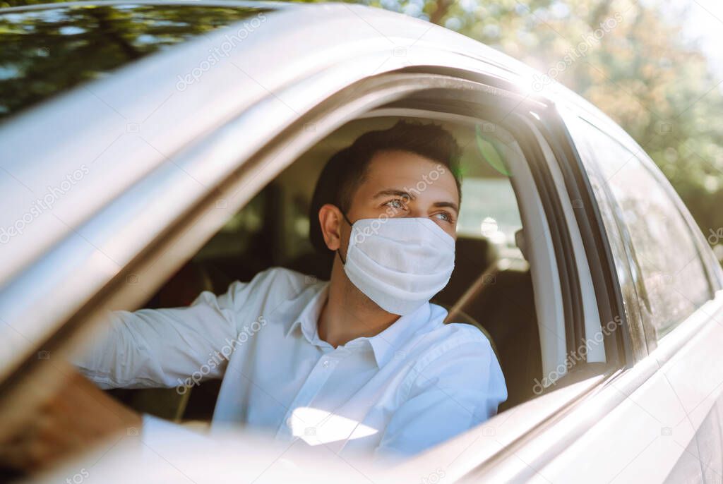 Man driving a car puts on a medical mask during an epidemic in quarantine city. Health protection, safety and pandemic concept. Covid- 19.