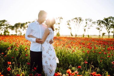Haşhaş tarlasında sevgili bir çift. Sevgili çift, Haşhaş Tarlası 'nda romantik bir buluşma sırasında birbirlerine sarılırlar. Birlikte eğleniyoruz. Gençlik, aşk ve yaşam tarzı kavramı.