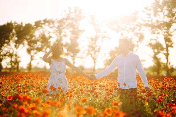 Loving couple in the poppy field. Loving couple hug one another during romantic date in poppy field. Enjoying time together. The concept of youth, love and lifestyle.